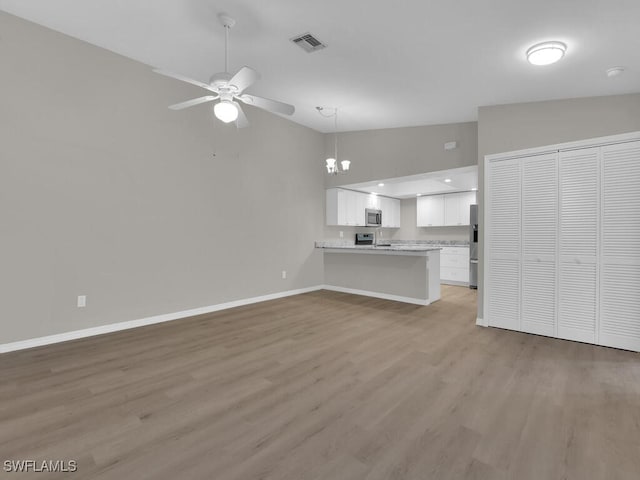 unfurnished living room with baseboards, visible vents, vaulted ceiling, light wood-style floors, and ceiling fan with notable chandelier