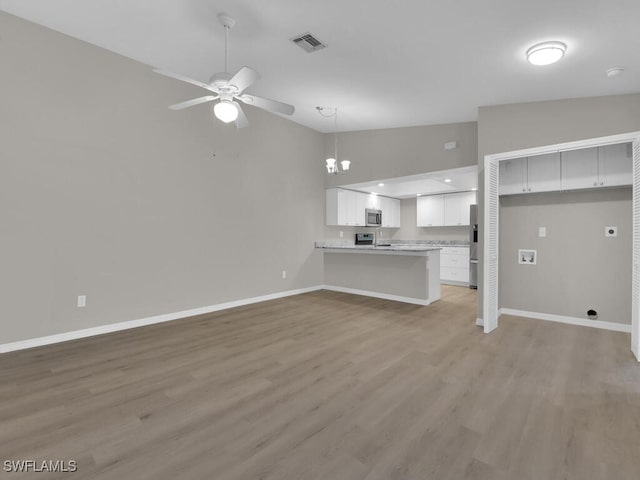 unfurnished living room featuring vaulted ceiling, light wood finished floors, visible vents, and baseboards