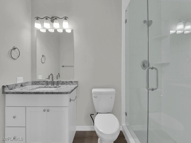 full bath featuring toilet, a shower stall, baseboards, and vanity