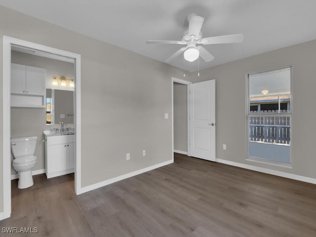 unfurnished bedroom featuring a ceiling fan, a sink, ensuite bath, wood finished floors, and baseboards