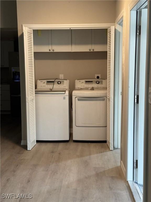 laundry area with washer and clothes dryer, cabinet space, and light wood-style floors