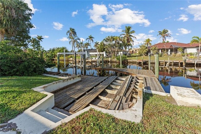 view of dock with a water view and a lawn