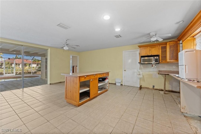 kitchen with tasteful backsplash, kitchen peninsula, ceiling fan, and white refrigerator