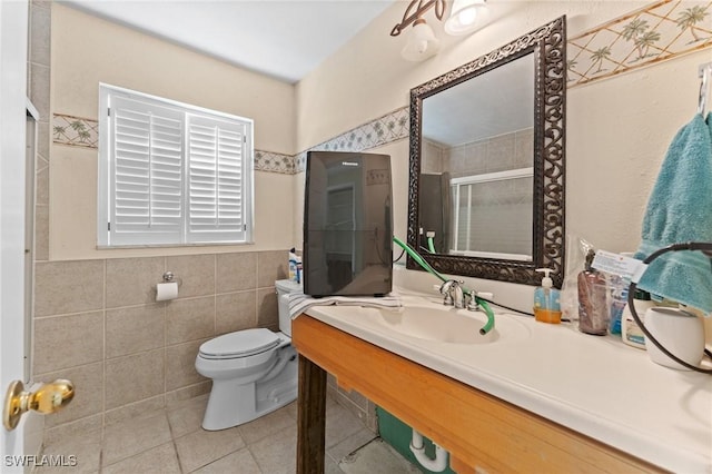 bathroom with sink, a shower with door, tile patterned flooring, tile walls, and toilet