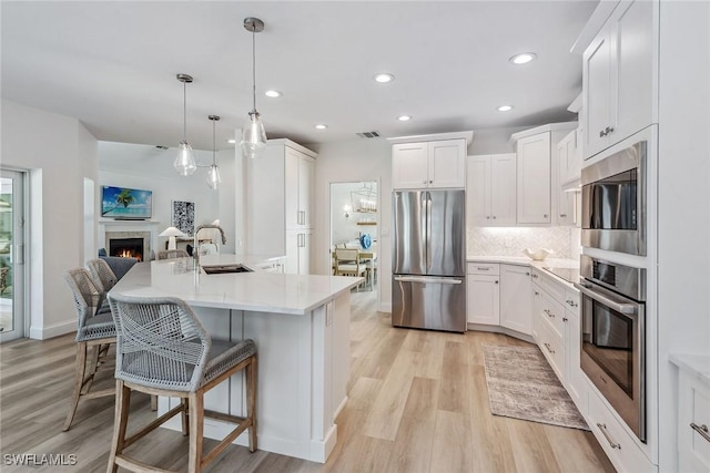 kitchen featuring tasteful backsplash, hanging light fixtures, stainless steel appliances, and white cabinets