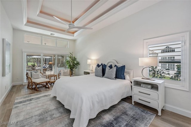 bedroom with crown molding, a tray ceiling, wood-type flooring, and ceiling fan