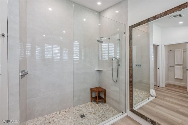 bathroom with a tile shower and hardwood / wood-style flooring