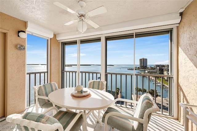 sunroom / solarium with a water view and ceiling fan