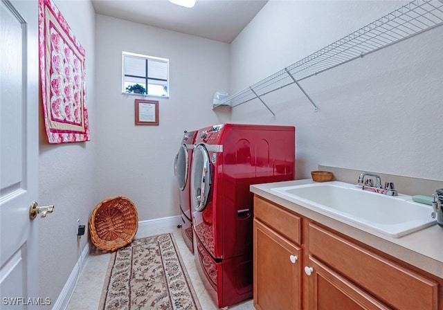 clothes washing area with cabinet space, light tile patterned floors, baseboards, independent washer and dryer, and a sink