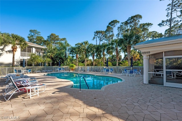 community pool with a sunroom, a patio area, and fence