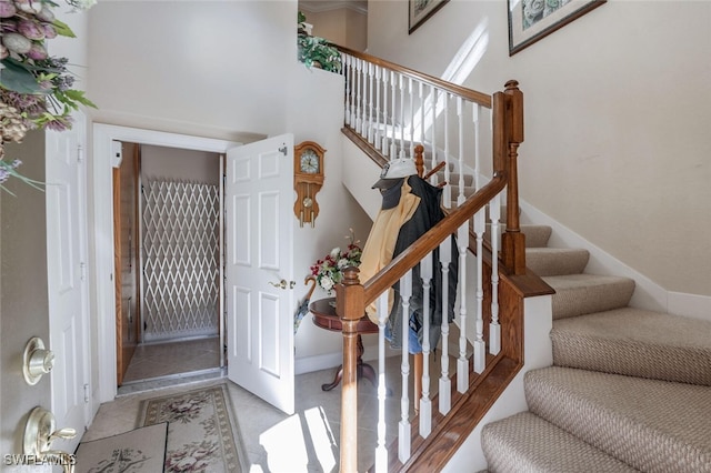 entryway featuring a high ceiling, stairway, and baseboards