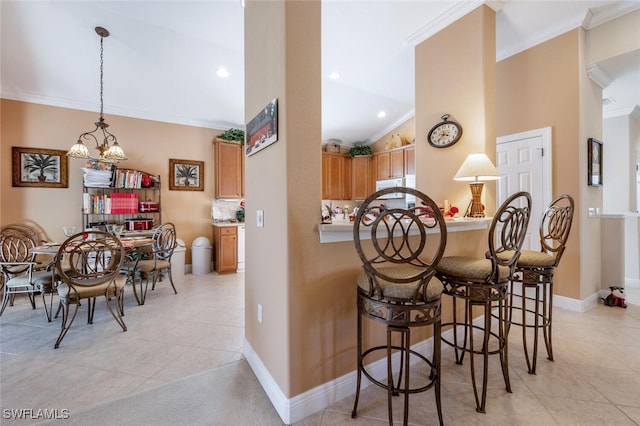 kitchen with lofted ceiling, baseboards, ornamental molding, and a kitchen breakfast bar