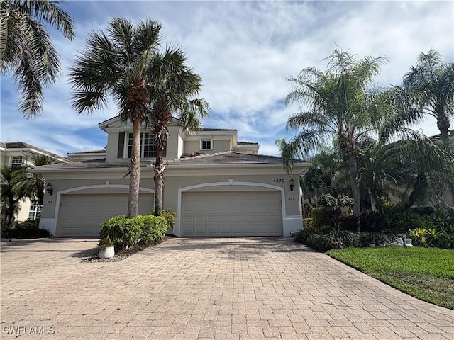 view of front facade featuring an attached garage, decorative driveway, and stucco siding