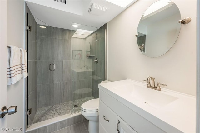 bathroom featuring vanity, a shower with shower door, and toilet