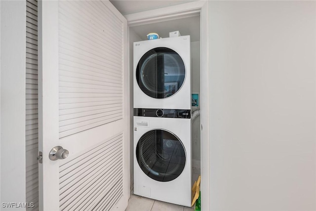 laundry room featuring stacked washer / drying machine and light tile patterned floors