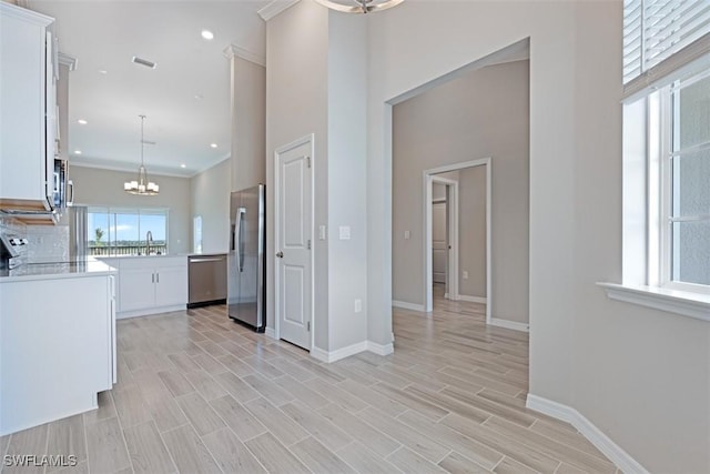 kitchen featuring baseboards, a chandelier, light countertops, white cabinets, and appliances with stainless steel finishes