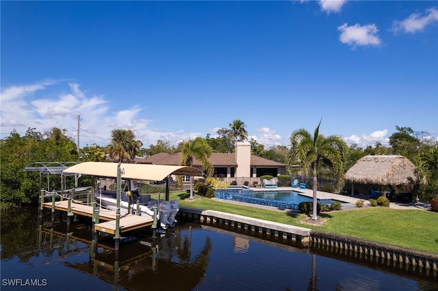 dock area with a water view, boat lift, a fenced in pool, and a yard