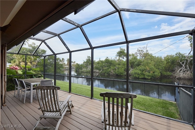 wooden deck with a water view, glass enclosure, and a lawn