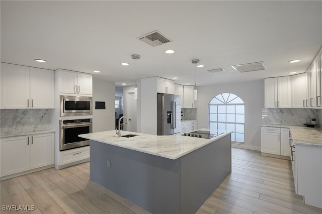 kitchen featuring white cabinets, visible vents, stainless steel appliances, and a sink