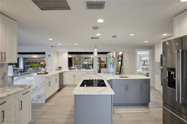 kitchen with visible vents, high end refrigerator, black electric stovetop, and a center island with sink