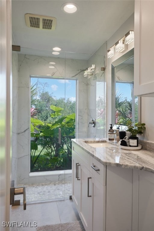 bathroom featuring visible vents, vanity, and a marble finish shower