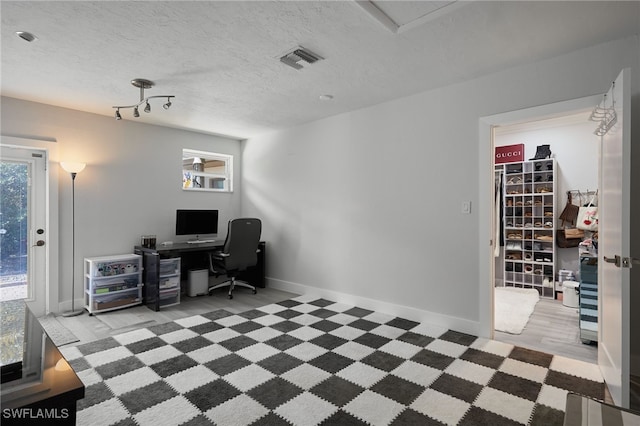 home office featuring visible vents, a textured ceiling, and baseboards