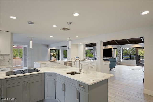 kitchen with backsplash, black electric cooktop, a sink, and gray cabinetry