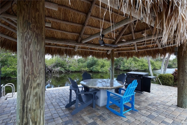 view of patio / terrace with ceiling fan, a gazebo, outdoor dining area, and a water view