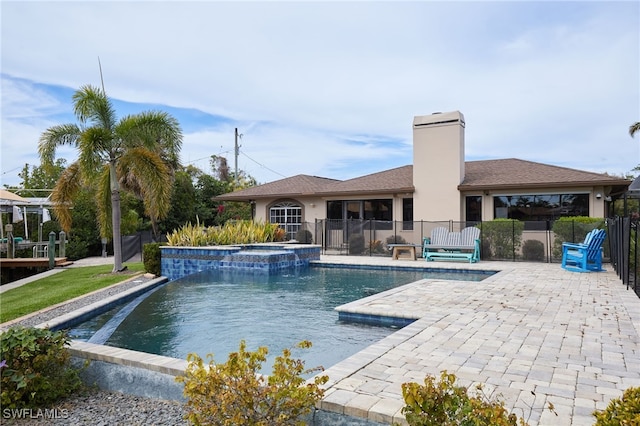 view of swimming pool featuring a patio area, a pool with connected hot tub, and fence