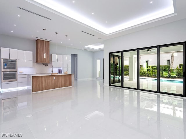 kitchen with light countertops, hanging light fixtures, white cabinetry, a kitchen island, and modern cabinets