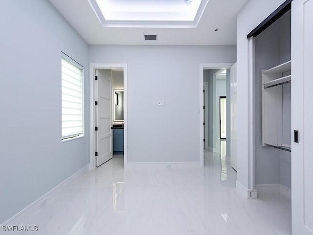 hall with marble finish floor, a raised ceiling, visible vents, and baseboards