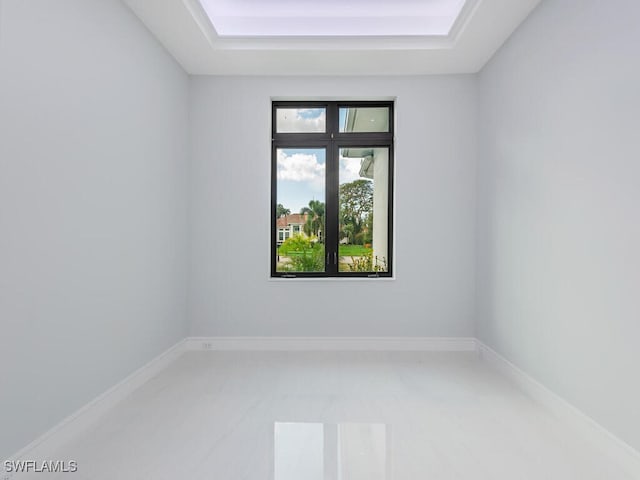 empty room featuring a raised ceiling and baseboards