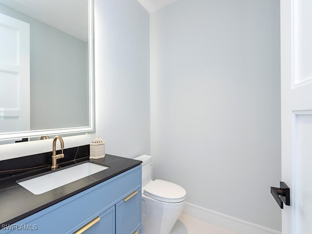 bathroom with toilet, baseboards, and vanity