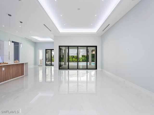 spare room featuring a raised ceiling and baseboards