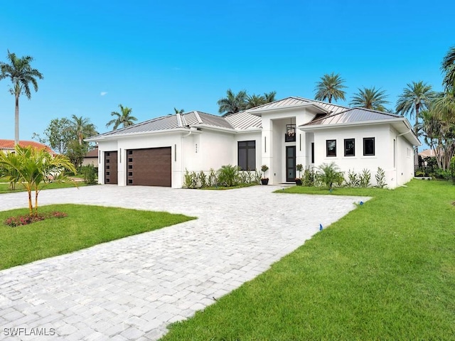 view of front of house with an attached garage, decorative driveway, a standing seam roof, and a front yard