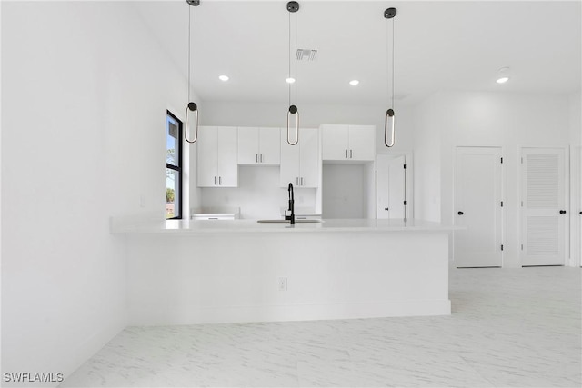 kitchen featuring pendant lighting, kitchen peninsula, sink, and white cabinets