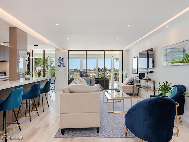 living area featuring recessed lighting, expansive windows, and light wood-style floors