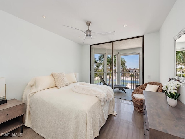 bedroom with a wall of windows, access to exterior, a ceiling fan, and dark wood-type flooring