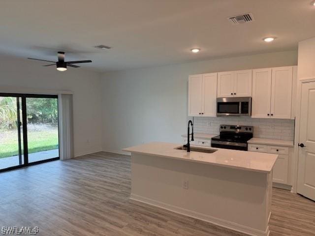 kitchen with stainless steel appliances, a center island with sink, and white cabinets