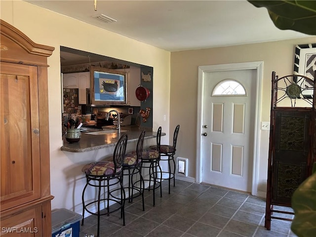 foyer featuring wet bar and dark tile patterned flooring