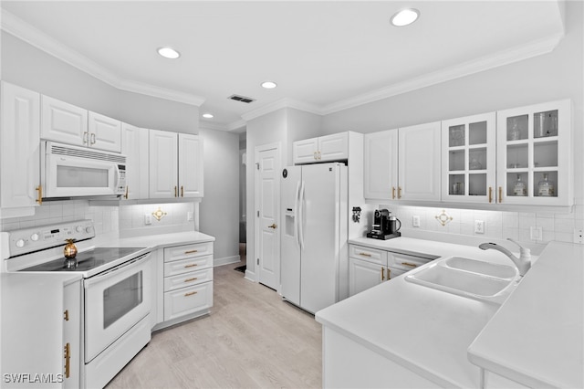 kitchen with white appliances, ornamental molding, sink, and white cabinets