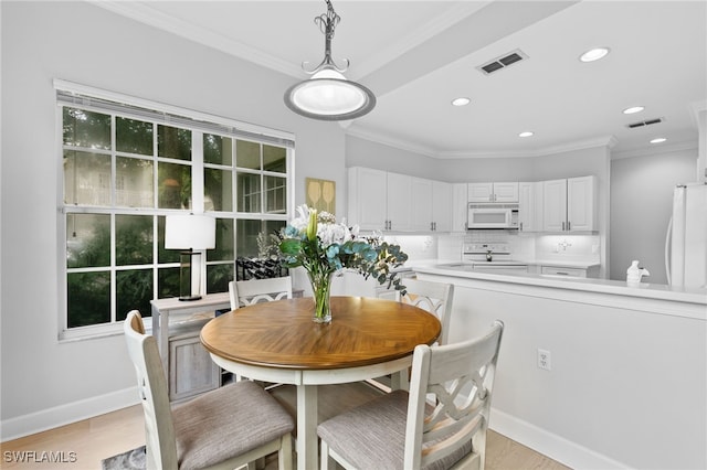 dining room with ornamental molding and light wood-type flooring