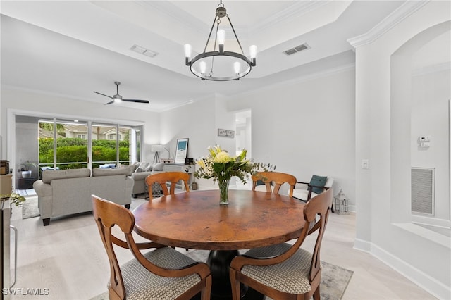 dining area featuring ornamental molding, a raised ceiling, and ceiling fan with notable chandelier