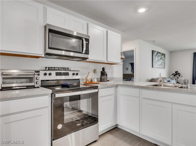 kitchen featuring white cabinets, stainless steel appliances, a sink, and light countertops