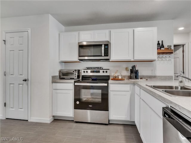 kitchen with open shelves, white cabinets, stainless steel appliances, and a sink