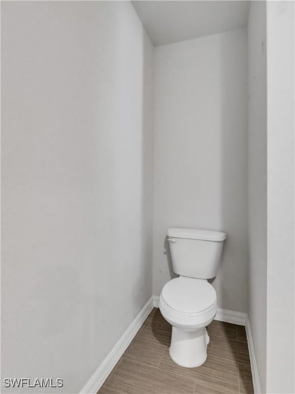 bathroom with toilet, baseboards, and wood finished floors