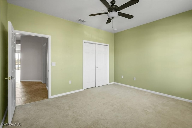 unfurnished bedroom with light carpet, ceiling fan, and a closet