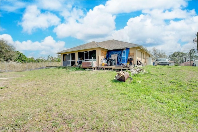 rear view of property with a wooden deck, a sunroom, and a lawn