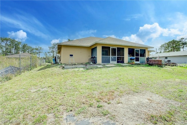 back of house with a yard, a hot tub, and a sunroom