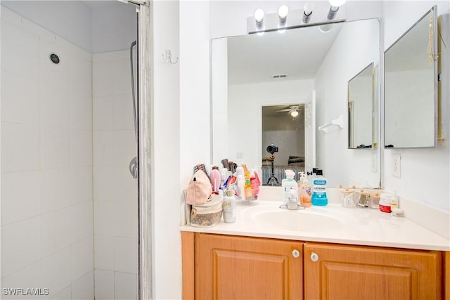 bathroom with vanity, ceiling fan, and tiled shower